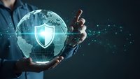 Businessman holding holographic globe with security shield icon representing global cybersecurity protection and digital network safety solutions.