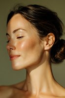 Young Asian woman with glowing natural skin and closed eyes in profile view, showing minimal makeup and dewy complexion against olive background. Wellness and skincare concept.