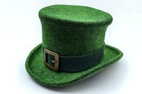 Green felt top hat with black band and golden buckle on white background, traditional Irish symbol for St Patrick's Day celebration and luck.