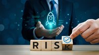 Businessman in suit holding glowing rocket icon above wooden blocks spelling RISK with checkmark, representing startup launch and business risk management.