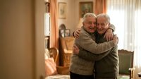 Happy senior couple embracing in cozy living room showing love and affection in retirement years together at home.