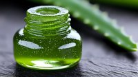 Fresh aloe vera extract in glass bottle with natural leaf on dark stone background, organic skincare ingredient for cosmetic and wellness products.