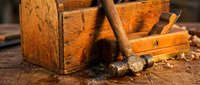 Vintage wooden toolbox with traditional woodworking chisels and hand tools on rustic workbench. Classic carpentry equipment for craftsmanship projects.