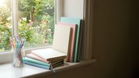 Cozy reading nook with stack of books and pencils by sunny window overlooking garden. Perfect for studying, learning, and educational content creation.