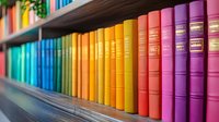 Colorful rainbow collection of books arranged by spectrum colors on wooden library shelf, creating vibrant educational atmosphere for reading and learning.