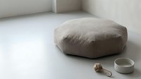 Minimalist meditation corner with beige floor cushion and ceramic bowl in neutral modern interior space for mindfulness practice and relaxation.