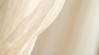 Soft beige linen fabric with delicate texture and natural fibers, flowing curtain material in warm neutral tones for interior design and home decor projects.
