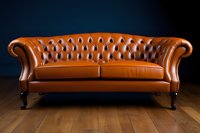 Luxurious brown leather Chesterfield sofa with classic diamond tufted pattern and rolled arms on wooden floor against dark wall, elegant furniture piece.