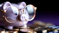 Pink piggy bank wearing round glasses surrounded by scattered coins on dark background for financial planning and savings concepts.