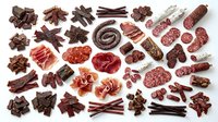 Assorted cured meats and charcuterie including salami, prosciutto, beef jerky and sausages arranged on white background for food styling and culinary design projects.