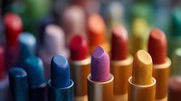 Colorful array of metallic and glittery lipsticks arranged in a row showing vibrant shades of blue, purple, gold and red, creating a glamorous makeup display.