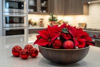 Red poinsettia plant with Christmas ornaments in wooden bowl on modern kitchen counter. Holiday home decoration for festive seasonal interior design.