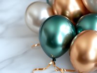 Metallic balloons in emerald green, rose gold and pearl white with ribbons create elegant party decoration against marble background for celebrations.