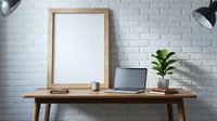Wooden frame mockup on desk with laptop, plant and supplies against white brick wall for design.