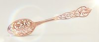 Ornate copper spoon with intricate floral engravings and decorative handle on light background for culinary and kitchen design projects.