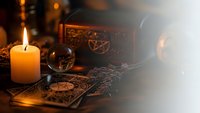 Mystical tarot cards with crystal ball and burning candle create atmospheric fortune telling scene for spiritual guidance and divination practices.