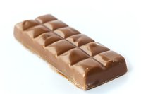 Milk chocolate bar with classic rectangular segments photographed on white background, showing texture and glossy surface for confectionery and food marketing.
