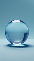 Transparent glass sphere with blue reflections on soft turquoise background, creating elegant minimalist composition with subtle shadows and light effects.