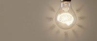 Glowing lightbulb with brain inside surrounded by business icons representing innovation, creativity and entrepreneurial thinking for corporate presentations.