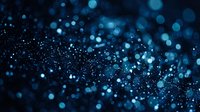 Abstract blue bokeh lights with sparkling glitter particles creating magical atmosphere for luxury backgrounds, celebrations, and festive designs.