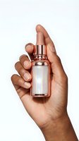 Female hand holding rose gold serum bottle with holographic label on white background for skincare and beauty product advertising.