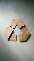 Recycling symbol made from crumpled kraft paper bags arranged on concrete surface, representing environmental sustainability and eco-friendly waste management practices.
