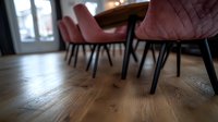 Modern pink velvet dining chairs with black metal legs on wooden floor in restaurant interior, shallow depth of field perspective focusing on floor texture.