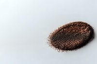 Ground coffee powder scattered in oval shape on white surface, macro shot with selective focus showing texture and granules of fresh roasted coffee.