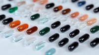 Colorful pharmaceutical capsules and pills arranged in organized rows on white background. Medical supplements and medication display for healthcare concepts.
