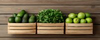 Fresh green produce arranged in wooden crates on rustic background - avocados, parsley and limes creating minimalist composition for healthy eating and food styling.