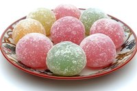 Colorful sugar-coated fruit gummy candies arranged on decorative glass plate isolated on white background for confectionery and sweet treat designs.