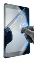 Hand applying protective screen film to tablet device with blue tint, showing installation process for device protection and maintenance.