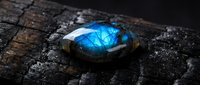 Stunning labradorite gemstone with brilliant blue flash on dark weathered wood surface showcasing natural mineral beauty and mystical properties for jewelry design.