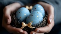 Female hands holding small nest with light blue Easter eggs decorated with gold polka dots and delicate bow, creating elegant holiday composition on dark background.