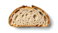 Artisan sourdough bread slice showing airy crumb structure with large holes, rustic crust and traditional fermentation texture isolated on white background.