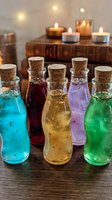 Colorful glass bottles with cork stoppers containing magical potions arranged on wooden surface with candles and vintage books creating mystical atmosphere.