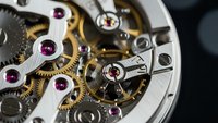 Intricate mechanical watch movement with golden gears, ruby jewels and precision components showcasing luxury timepiece craftsmanship and horological engineering.