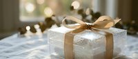 Elegant white gift box with gold ribbon bow on table with warm bokeh lights creating festive holiday atmosphere for celebrations and special occasions.