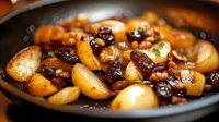 Caramelized pearl onions with dried cranberries in cast iron skillet, golden brown glazed vegetables for holiday side dish cooking and gourmet recipes.