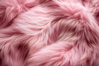 Soft pink faux fur texture background with fluffy waves and gentle shadows creates luxurious textile surface pattern for fashion and interior design projects.