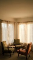 Cozy corner seating area with vintage armchairs and sheer curtains in warm natural light for interior design and home decor projects.