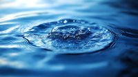 Macro shot of water drop impact creating crown splash and ripples on blue water surface with detailed liquid dynamics and light reflection.