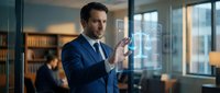 Professional businessman in navy suit using futuristic holographic interface technology in modern glass office environment for digital innovation concepts.