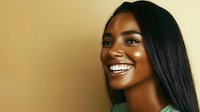 Young African American woman with bright white smile and long straight black hair against warm golden background, radiating joy and confidence in profile view.