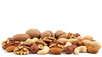 Mixed nuts collection with almonds walnuts cashews hazelnuts pecans on white background isolated for healthy snacking cooking baking nutrition concepts.