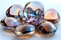 Sparkling crystal gems arranged in flower pattern with iridescent reflections and rainbow light effects on white surface, luxury jewelry concept.