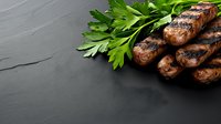 Grilled sausages with fresh parsley leaves on black stone background, corner composition with copy space for menu or recipe design.