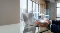 Businessman hand holding holographic digital interface with data analytics in modern office workspace for technology and business innovation.
