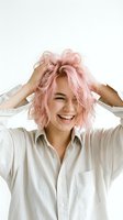 Young woman with East Asian ethnicity wearing white button-up shirt, styling voluminous pink wavy hair with both hands, smiling brightly against white background. Fashion and beauty content.