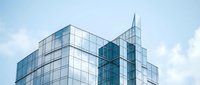Modern glass office buildings with reflective facades against blue sky with white clouds creating contemporary urban architecture for business concepts.
